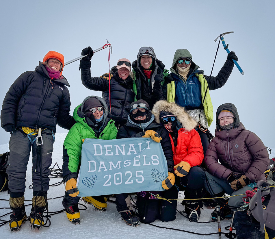 The 2025 all-women team on the summit of Denali holding a Denali Damsels banner